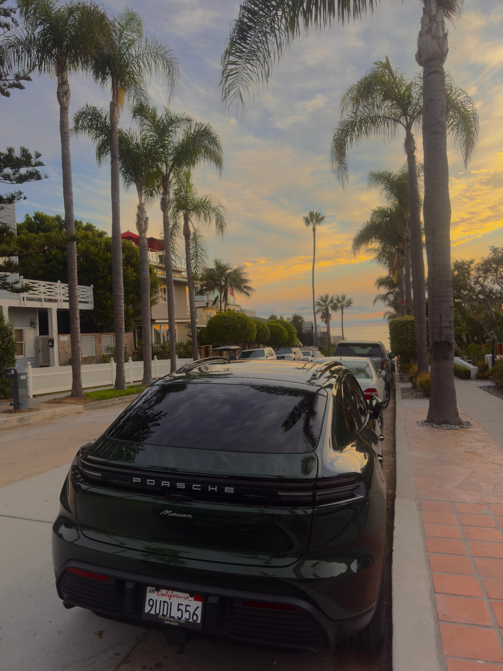 Green Porsche Macan parked on a palm-lined street at sunset in La Jolla California